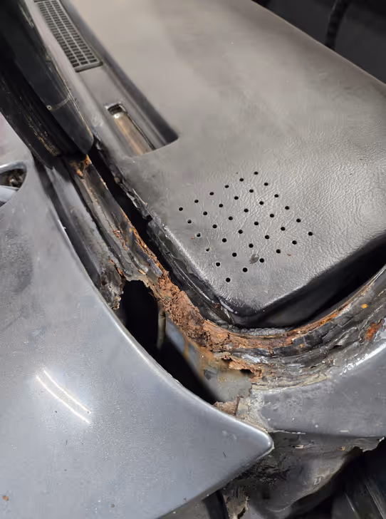 Severe rust damage on car cowl and windshield frame before restoration