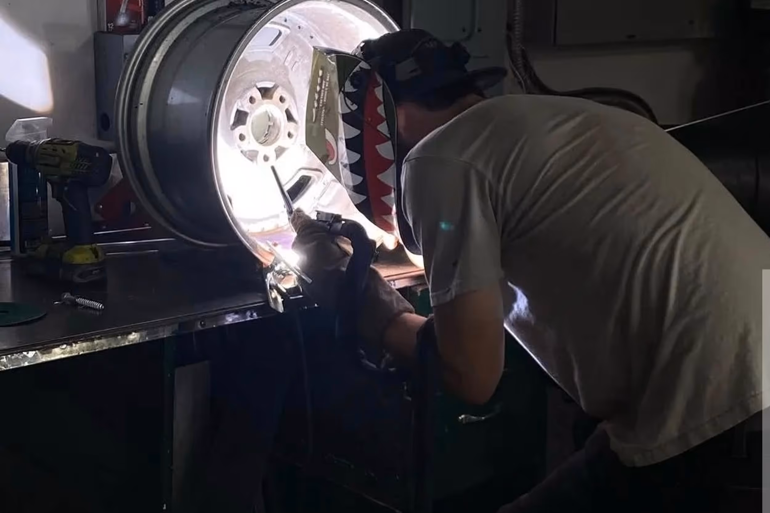 A skilled technician performing a precise TIG weld on the inside of a custom aluminum wheel.