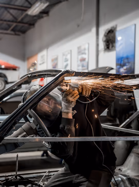 Grinding car frame with sparks highlighting the repair area